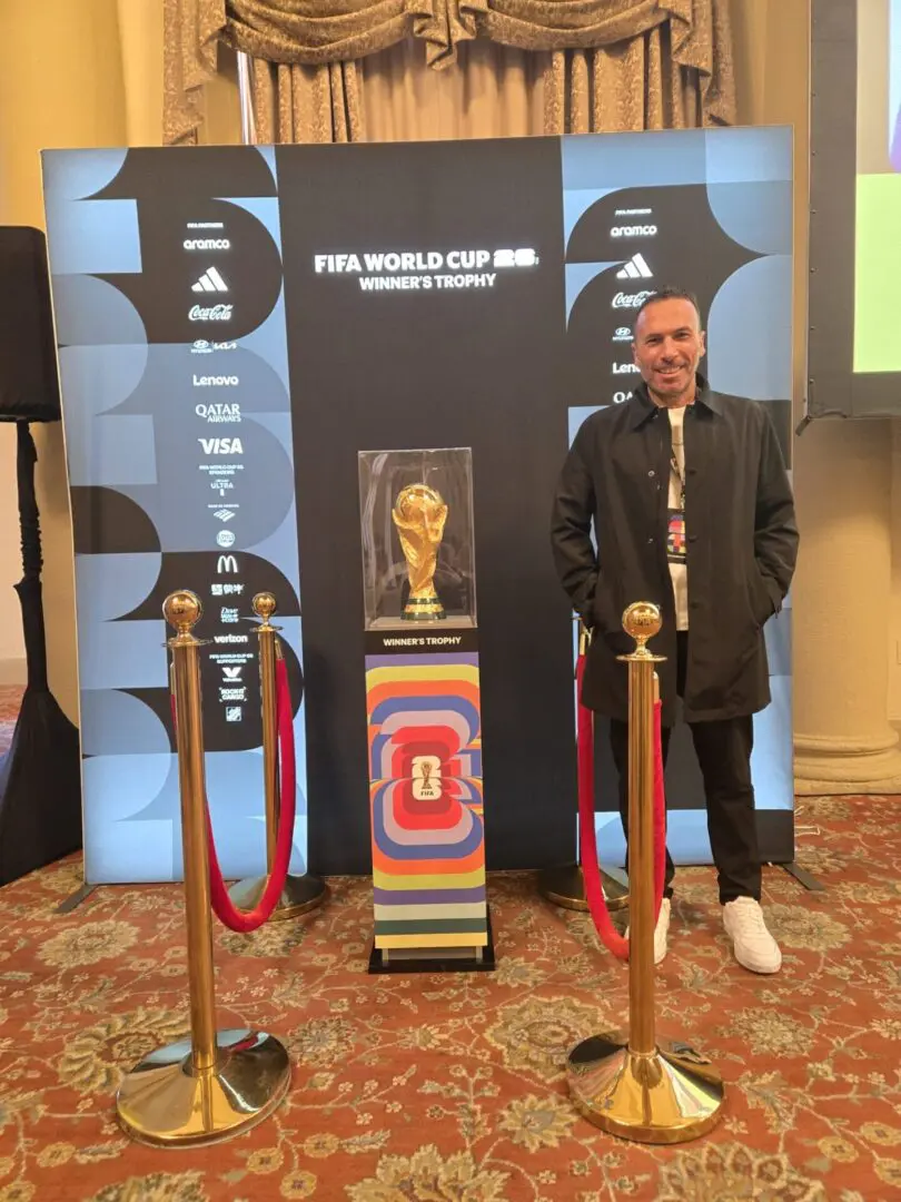 Man standing by FIFA World Cup trophy. Man standing by FIFA World Cup trophy.